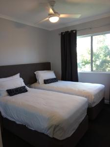 two beds in a room with a window at Oasis Private 2 Bed Apartment in Caloundra