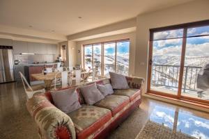 a living room with a couch and a large window at Sambuca in Mount Hotham