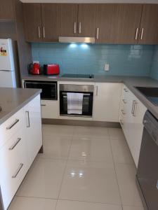 uma cozinha com armários brancos e um forno com placa de fogão em Oasis Private 2 Bed Apartment em Caloundra