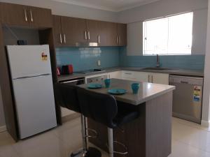 uma cozinha com um frigorífico branco e uma mesa com cadeiras em Oasis Private 2 Bed Apartment em Caloundra