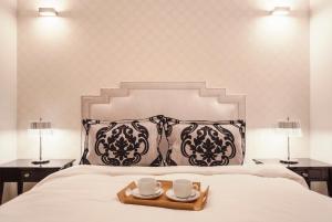 a tray with two cups on a bed with two lamps at Świętojańska Old Town Deluxe Apartament in Warsaw