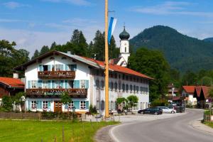 ein weißes Gebäude mit einem Uhrturm auf einer Straße in der Unterkunft Gasthof Jachenau in Jachenau