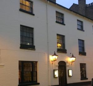 a white house with windows and lights on it at The Rugby Hotel in Rugby