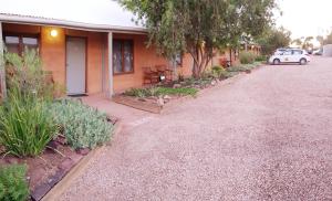 a house with a car parked next to a driveway at Mud Hut Motel in Coober Pedy