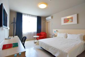 um quarto de hotel com uma cama e uma cadeira vermelha em Jinjiang Inn Shanghai Pudong Jichangzhen em Xangai