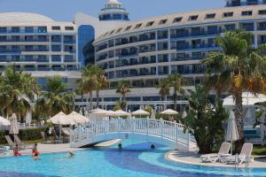 a pool at a resort with a bridge and a building at Sueno Hotels Deluxe Belek in Belek