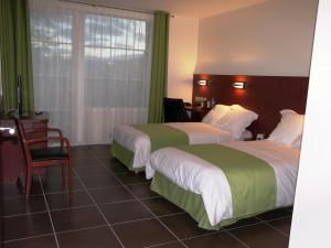 Hostellerie Del Matin Calme في Montverdun: غرفة فندقية بسريرين وطاولة وكراسي