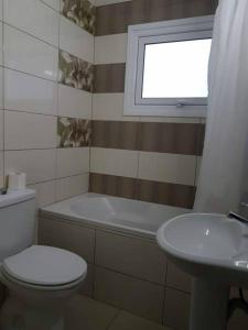 a bathroom with a toilet and a sink and a window at Marianna Hotel Apartments in Limassol
