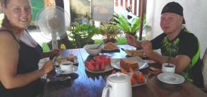 Um homem e uma mulher sentados à mesa com comida. em Tropical Garden em Negombo