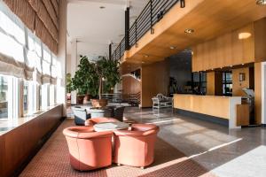 un vestíbulo con taburetes naranjas y mesas en un edificio en FlyOn Hotel & Conference Center, en Bolonia