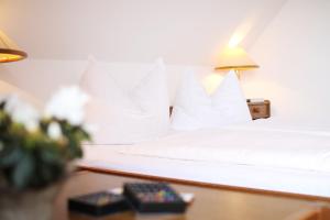 a bed with white pillows and a lamp on a table at Landhotel & Reiterhof Schumann in Triptis