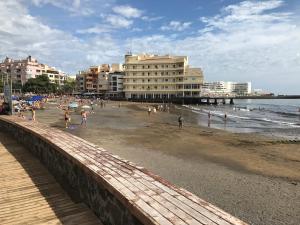 a beach with buildings and people on the beach at La Perla Medano 2 in El Médano