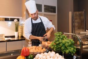 a man in a chefs hat preparing food in a kitchen at Sofitel London Gatwick in Horley