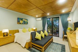 een slaapkamer met een kingsize bed en een stoel bij Villa De Campagne Hoi An in Hội An