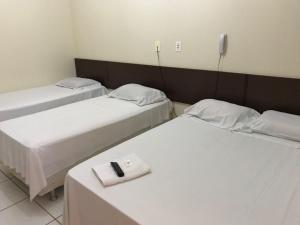 a room with two beds and a table with a remote control at Lider Hotel in Jataí