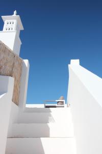 a stairway leading up to a white building with a blue sky at Casa Opala Townhouse met Rooftop Pool in Olhão
