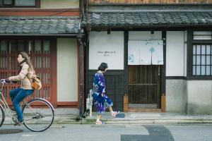 two women walking down the street with a bike at Casa OGUMO in Kyoto