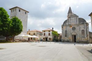 an old building with a clock tower and a church at Guest House Mareda Palms in Novigrad Istria