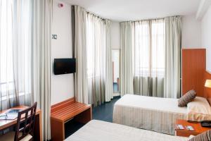 um quarto de hotel com duas camas e uma secretária em Hotel Florence em Lourdes