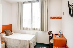 a bedroom with a bed and a desk and a window at Hotel Florence in Lourdes