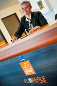 a young woman sitting at a desk with a poster at Hotel Florence in Lourdes