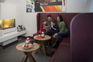 a family sitting on a couch in a living room at Jugendherberge Berlin Ostkreuz in Berlin