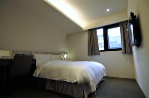 a bedroom with a white bed and a window at 泊居旅店二館 Oursinn Hotel 2 in Taipei