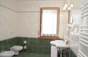 フォルノ・ディ・ゾルドにあるHotel Garnì postaのバスルーム(トイレ、洗面台付)、窓が備わります。