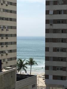 uma vista para a praia entre dois edifícios em Apartamento Pitangueiras no Guarujá