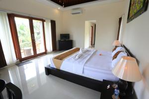 a bedroom with a large bed in a room with windows at Luna Llena Villas in Ubud