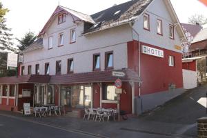 ein rotes Gebäude mit Tischen und Stühlen davor in der Unterkunft Hotel Ristorante Ätna in Ulrichstein