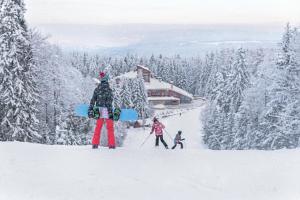 a person holding a snowboard on top of a ski slope at Hotel Yastrebets Wellness & Spa in Borovets