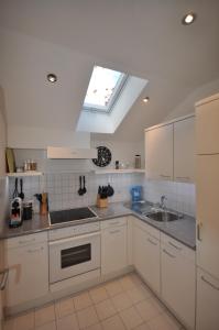 eine Küche mit weißen Schränken, einem Waschbecken und einem Dachfenster in der Unterkunft Apartment am Mohrenplatz in Garmisch-Partenkirchen