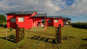 una casa roja con una valla delante en Ruka Inka en Villa Yacanto
