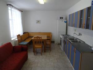 a kitchen with a red couch and a table and a kitchen with a tablektop at U Nás - Apartmán Jelen in Vápenná