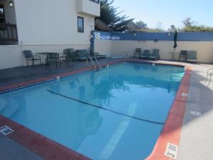 una gran piscina azul con sillas y mesas. en Monterey Fairgrounds Inn en Monterrey