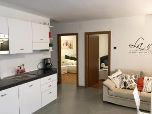 リーヴァ・デル・ガルダにあるL'Angolo di Edda -の白いキャビネットとソファ付きのキッチン、ベッドルーム1室が備わります。