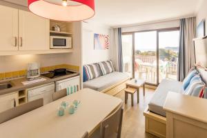 a small kitchen and a living room with a table at Résidence Pierre & Vacances l'Ange Gardien in Villefranche-sur-Mer