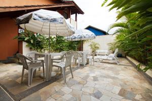 un patio con mesas, sillas y una sombrilla en Residencial Elenita, en Boicucanga