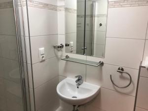 a white bathroom with a sink and a shower at Hotel Gambrinus Dutenhofen in Wetzlar