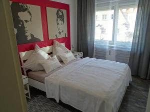 1 dormitorio con cama blanca y pared roja en Steinhauser`s Ferienwohnungen en Augsburg