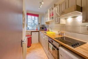 uma cozinha com armários brancos e um forno com placa de fogão em JOIVY Stylish Castle View Apartment em Edimburgo