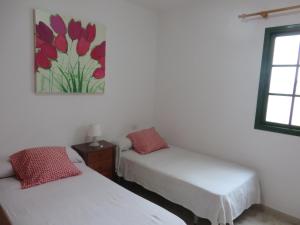 カレタ・デ・ファマラにあるCoqueto apartamentoのベッドルーム1室(ベッド2台付)が備わります。壁には絵画が飾られています。