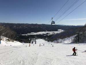 a group of people skiing down a snow covered ski slope at Sunny Side Hut in Hakuba