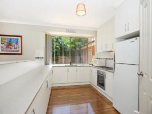 a kitchen with white cabinets and a large window at All Seasons Port Elliot Holiday House in Port Elliot