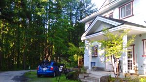 a blue car parked in front of a white house at Sunny Side Hut in Hakuba