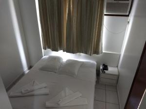 uma cama branca num quarto com uma janela em Master Hotel em Balneário Camboriú