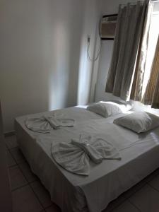 uma cama branca com dois pares de sapatos em Master Hotel em Balneário Camboriú