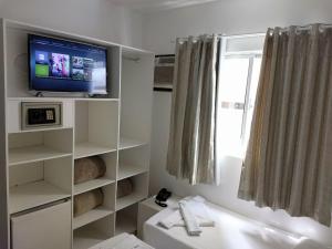uma casa de banho com uma televisão numa prateleira branca em Master Hotel em Balneário Camboriú