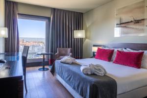 a hotel room with a bed, desk, chair and window at Melia Ria Hotel & Spa in Aveiro